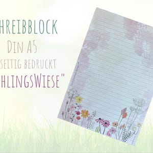 May include: A5 lined notepad with a floral design. The notepad features the text "SCHREIBBLOCK DIN A5 EINSEITIG BEDRUCKT 'FRÜHLINGSWIESE'" and a watercolour-style floral border with pink, yellow, and orange flowers.