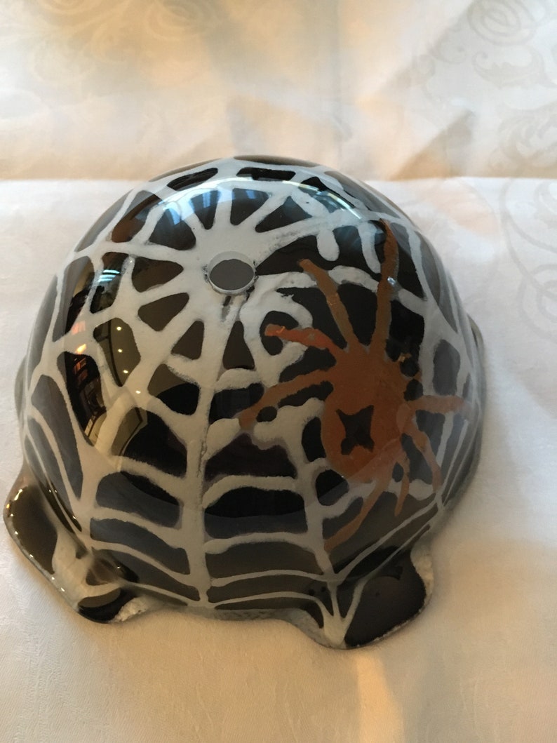 May include: Black ceramic bowl with a white spiderweb design and a brown spider in the center. The bowl has a hole in the top.