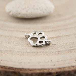 May include: Silver paw print charm with two jump rings. The charm is a cutout design and is perfect for adding to jewellery or crafts.