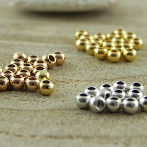 May include: Three groups of round metal beads, one group is gold, one is silver, and one is rose gold.