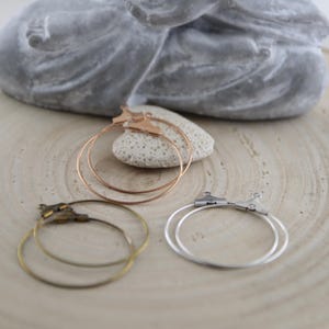 Könnte beinhalten: Drei Paar Creolen mit verschiedenen Verschlüssen. Die Creolen sind aus Metall und in Silber, Gold und Roségold erhältlich.