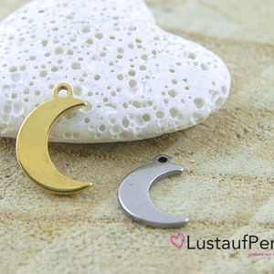 May include: Two crescent moon charms, one gold and one silver, on a white heart-shaped stone. The charms have a hole at the top for attaching to jewelry.