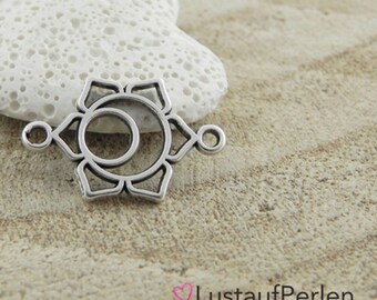 May include: Silver charm featuring a detailed outline of a chakra symbol. The charm has two loops on either side for attaching to a necklace or bracelet.