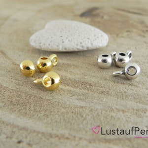 Könnte beinhalten: Goldene und silberne Metallperlenkappen mit einer Öse zum Anbringen an Schmuck oder andere Bastelarbeiten.
