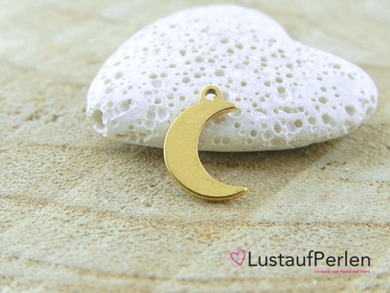 May include: Gold-colored metal crescent moon charm pendant. The charm is on a white heart-shaped rock.