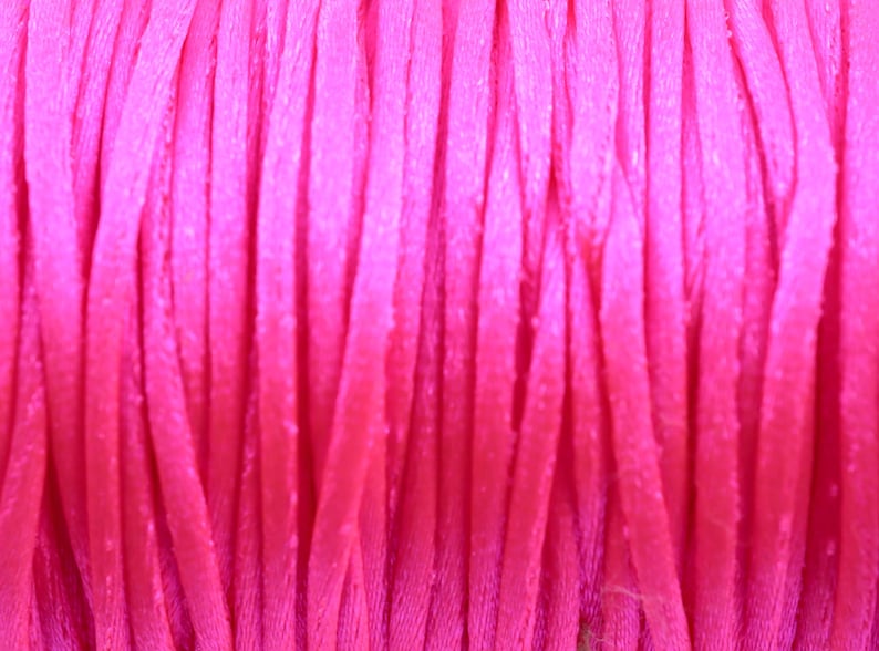 May include: Close-up of a spool of bright pink embroidery floss.