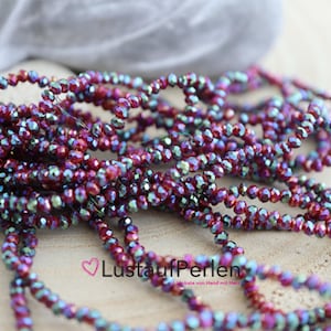 Könnte beinhalten: Eine Strähne aus facettierten Glasperlen in Rot und Grün mit irisierendem Effekt. Die Perlen sind klein und haben eine glänzende Oberfläche.