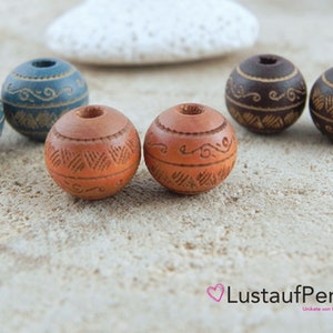 Könnte beinhalten: Sortiment aus Holzperlen mit aufwendigen Schnitzereien. Die Perlen sind in Braun-, Blau- und Schwarztönen gehalten.