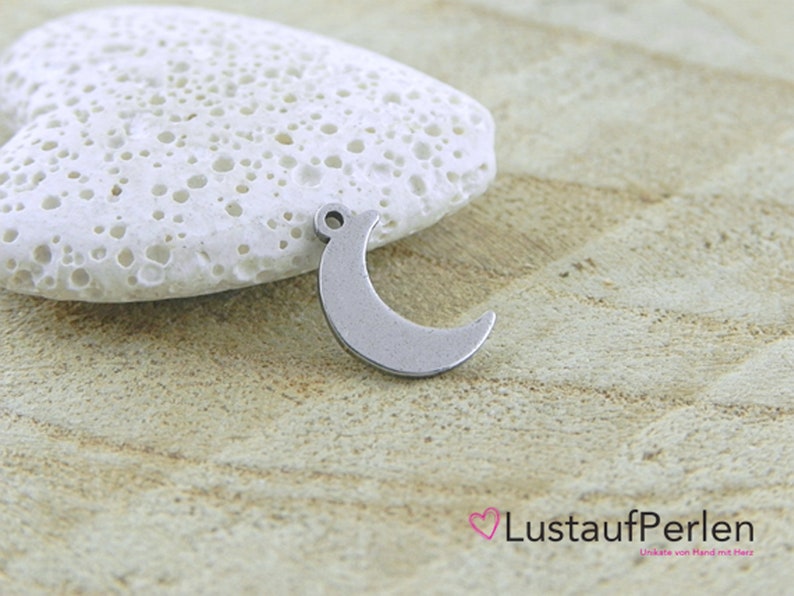 May include: A silver crescent moon charm with a loop for attaching to a necklace or bracelet.