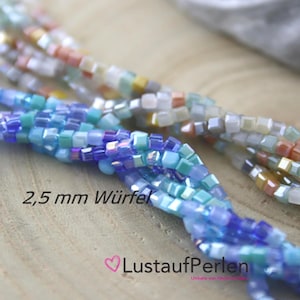 Könnte beinhalten: Nahaufnahme von mehreren Strängen würfelförmiger Perlen in Blau-, Grün- und Pfirsichtönen. Die Perlen sind etwa 2,5 mm groß. Der Text "LustaufPerlen" ist unten im Bild zu sehen.