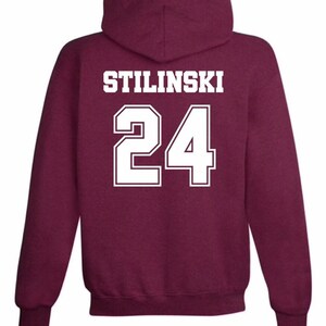 May include: Burgundy hooded sweatshirt with white text that reads "STILINSKI 24" on the back.