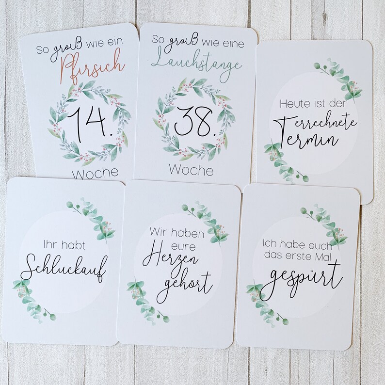 May include: Set of 6 white cards with green floral illustrations and black text. The cards feature milestones in pregnancy, such as the size of the baby, the due date, and the first time the baby's heartbeat was heard.