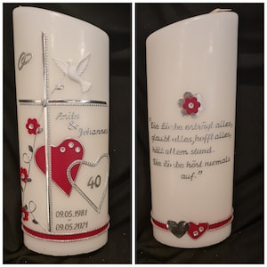 Könnte beinhalten: Eine weiße Kerze mit einem silbernen Kreuz und zwei roten Herzen. Die Kerze ist mit silbernen Perlen und roten Blumen verziert. Der Text "Anita & Johannes" und "40" ist auf der Kerze geschrieben. Die Daten "09.05.1981" und "09.05.2021" sind ebenfalls auf der Kerze geschrieben. Das Zitat "Die Liebe erträgt alles, glaubt alles, hofft alles, hält allem stand. Die Liebe hört niemals auf." ist auf der Kerze geschrieben.