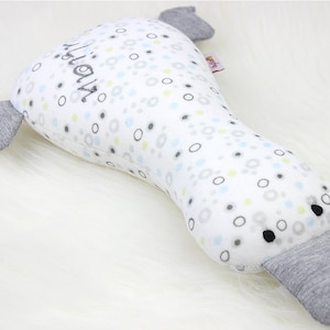 Può includere: Un cuscino di peluche a forma di ornitorinco con motivo grigio e bianco, occhi neri e la parola "platypus" ricamata sul lato.