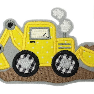 Könnte beinhalten: Gelber und schwarzer gestickter Bügelaufkleber eines Spielzeug-Baumaschinens, eines Baggers mit Schaufel. Der Bagger hat ein schwarz-weißes Karomuster auf den Rädern.