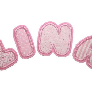 Peut inclure: Lettres en feutre rose orthographiant le nom "Lina" avec des motifs différents sur chaque lettre.