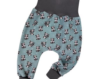 Op de afbeelding: Een babybroek in blauw en grijs met een wasbeerprint. De broek heeft een brede elastische tailleband en gezoomde pijpen.