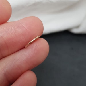 May include: A thin gold hoop earring, shown on a finger.