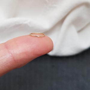Könnte beinhalten: Ein dünner goldener Ring, der an einem Finger getragen wird.
