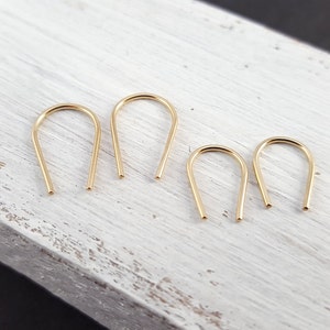 Pu&ograve; includere: Quattro orecchini a cerchio dorati con un design semplice e minimalista. Gli orecchini sono realizzati con un filo sottile e rotondo che &egrave; piegato a forma di U.