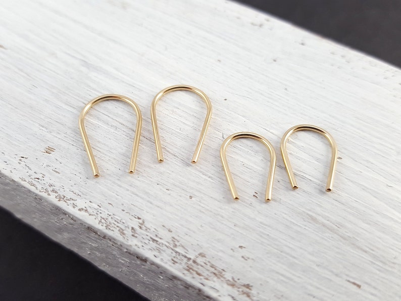Pu&ograve; includere: Quattro orecchini a cerchio dorati con un design semplice e minimalista. Gli orecchini sono realizzati con un filo sottile e rotondo che &egrave; piegato a forma di U.