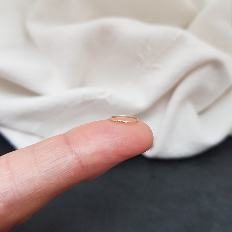May include: A thin gold ring, worn on a finger.