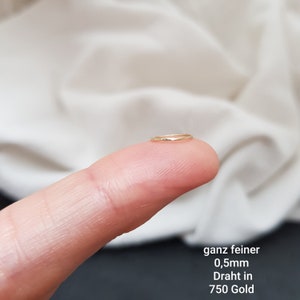 May include: A very thin gold ring, 0.5mm in diameter, made of 750 gold wire. The ring is shown on a finger.