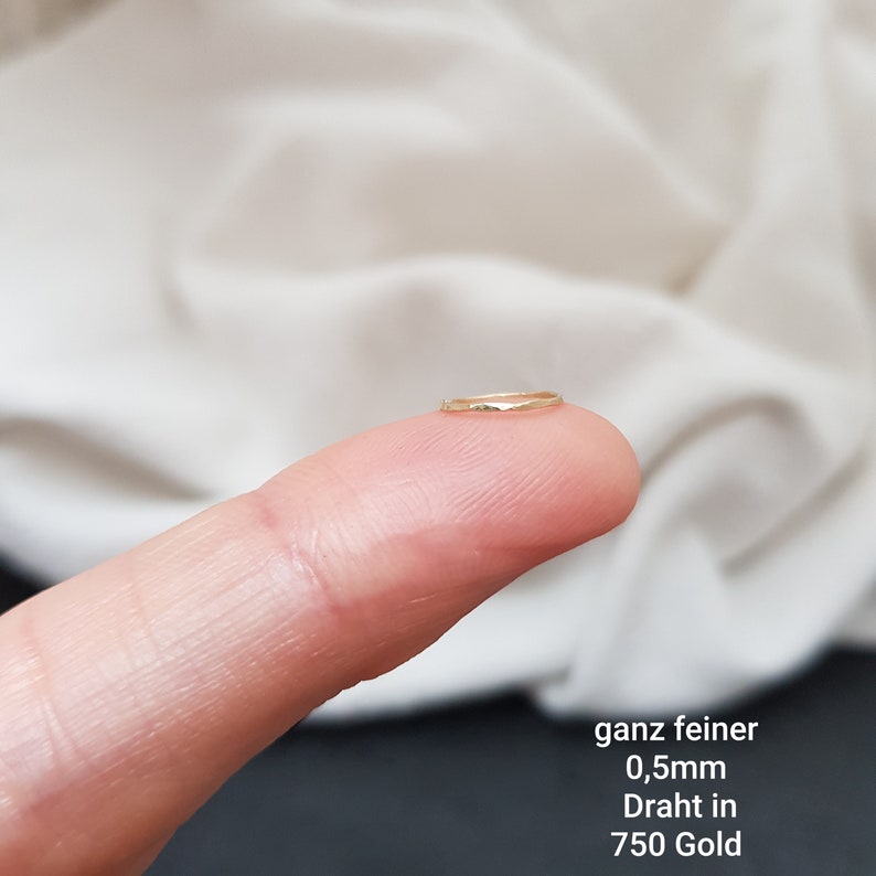 May include: A very thin gold ring, 0.5mm in diameter, made of 750 gold wire. The ring is shown on a finger.