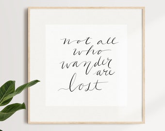 May include: A framed print with the quote "not all who wander are lost" written in black calligraphy on a white background.