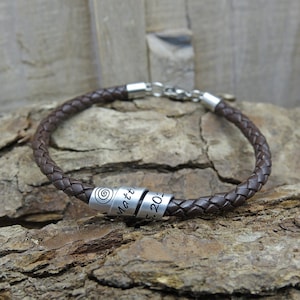 Könnte beinhalten: Ein braunes Lederarmband mit einer silbernen Perle, die mit dem Text "Matt" und "2015" graviert ist.