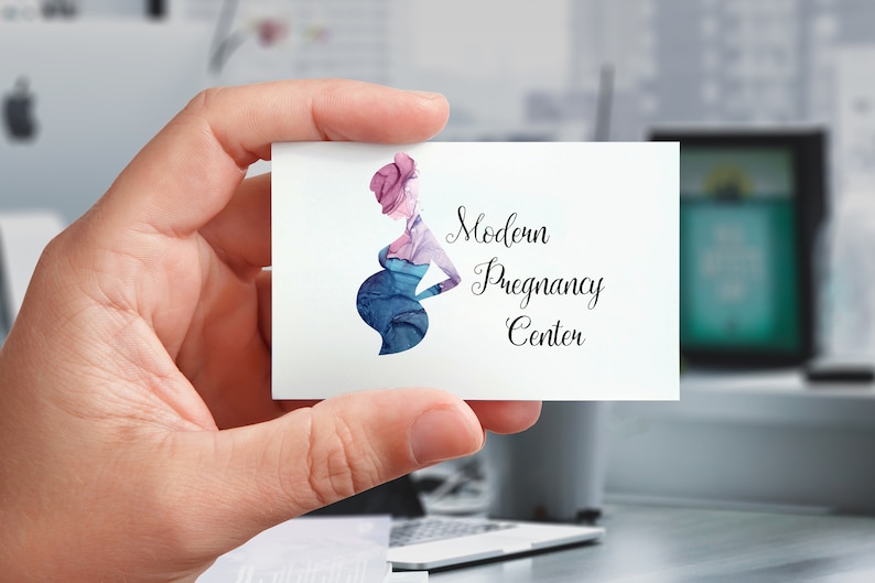 Puede incluir: Una tarjeta de visita sostenida en una mano, con una ilustraci&oacute;n en acuarela de una persona embarazada en tonos azules y morados. La tarjeta dice "Modern Pregnancy Center" en una elegante escritura.