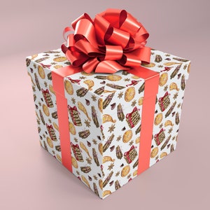 May include: A square gift box wrapped in white paper with a repeating pattern of festive illustrations in brown, red, and gold. The box is tied with a coral ribbon and topped with a large, matching bow. The background is a soft pink.