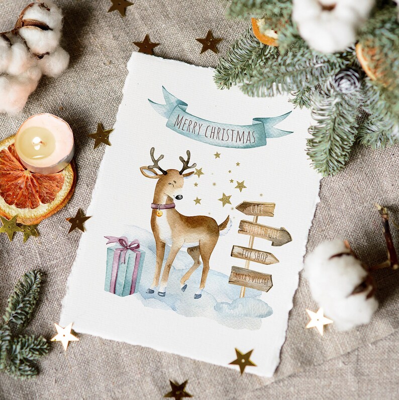 May include: A watercolor illustration of a reindeer standing in the snow with a gift box and wooden signs that read "Cafe", "North Pole", "Toy Shop", and "Santa's Village". The illustration is on a white background with gold stars and the text "Merry Christmas".