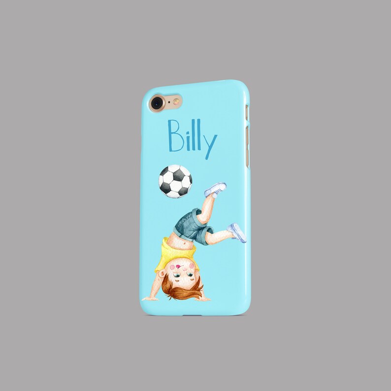 Pode incluir: Uma capa de telefone azul claro com uma ilustra&ccedil;&atilde;o de desenho animado de um menino fazendo uma parada de m&atilde;os com uma bola de futebol. O texto "Billy" est&aacute; impresso na capa.