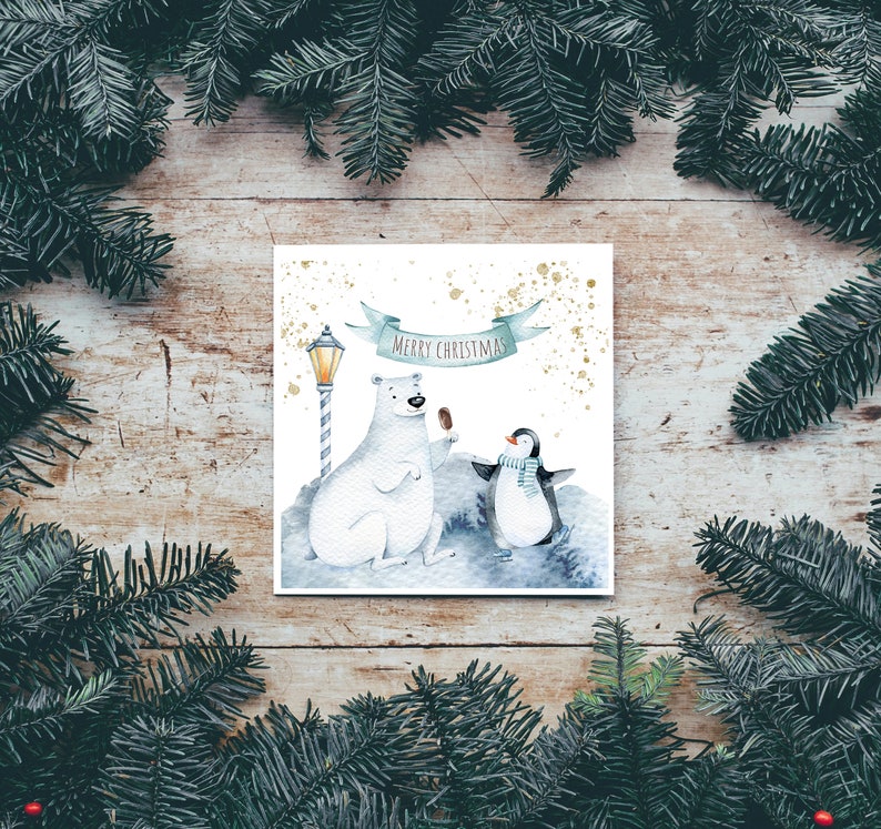 May include: A white card with a watercolor illustration of a polar bear and a penguin holding ice cream cones. The card has a blue banner with the text "Merry Christmas" and a gold glitter background.
