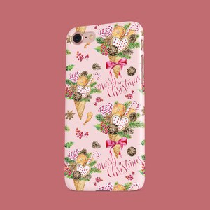 May include: A pink phone case featuring a repeating pattern of Christmas-themed ice cream cones. Each cone is decorated with cookies, candy, and berries, with a red bow. The words "Merry Christmas" are written in cursive.