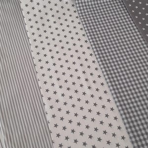 Könnte beinhalten: Vier verschiedene Stoffmuster in Grautönen. Die Muster sind horizontal angeordnet, mit einem Streifenmuster, einem weißen Stoff mit grauen Sternen, einem Gingham-Muster und einem einfarbigen grauen Stoff mit grauen Sternen.