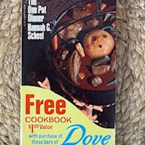 May include: A yellow and blue vintage cookbook cover with the text "Free Cookbook $1.00 Value with purchase of these bars of Dove ATLIDUAL PRICE". The cover features a photo of a pot of stew with vegetables and meat.