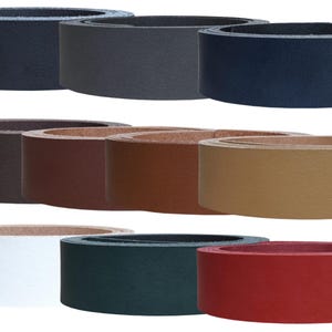 Könnte beinhalten: Eine Auswahl an Ledergürtelrohlingen in verschiedenen Farben: Schwarz, Grau, Marineblau, Braun, Beige, Weiß, Grün und Rot. Die Gürtel sind aufgerollt und zeigen ihre Textur und Farbvariationen. Geeignet für Bastelprojekte.