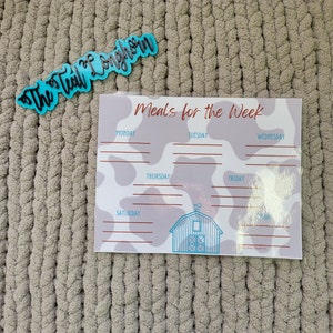 May include: A printable meal planner with a cow print background and a blue barn illustration. The planner is titled "Meals for the Week" and has spaces for each day of the week.