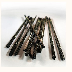 May include: A collection of thin, black metal scroll saw blades arranged in a cluster. Each blade features a fine, serrated edge designed for precision cutting, with a dark finish and a straight, slender profile suitable for detailed woodworking tasks.