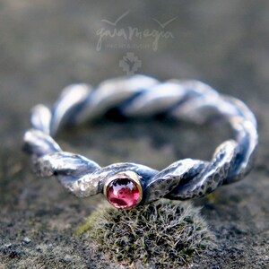 May include: A silver ring with a twisted band and a pink gemstone set in a gold bezel.