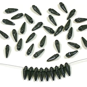 May include: A scattering of dark green glass beads with pointed tips, some are strung on a thin wire to form a necklace.