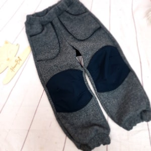 Könnte beinhalten: Graue Fleecehose mit dunkelblauen Knieschonern und Seitentaschen.