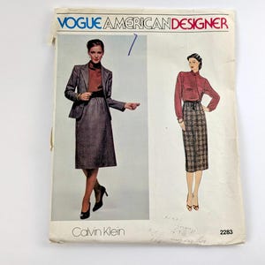 Pode incluir: Padrão de costura vintage Vogue American Designer com designs de Calvin Klein. A capa mostra ilustrações de mulheres em um terno de saia e blusa com uma saia xadrez. O número do padrão é 2283.