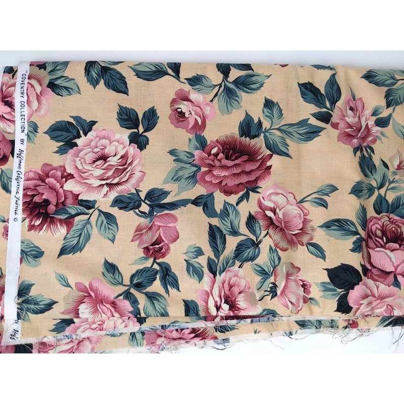 May include: Beige fabric with a floral print featuring pink and burgundy roses with green leaves. The fabric is labeled "Coventry Collection by Hoffman California Fabrics".