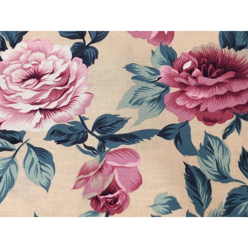 May include: Beige fabric with a floral pattern featuring pink roses and teal green leaves.
