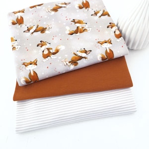 Könnte beinhalten: Drei Stoffmuster: eines mit einem sich wiederholenden Muster von Cartoon-Füchsen auf grauem Hintergrund, eines in einfarbigem Rost und eines mit grau-weißen Streifen. Der Fuchsstoff hat rote Herzen und weiße Sterne.