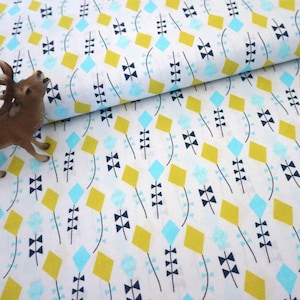 Può includere: Tessuto bianco con un motivo ripetuto di diamanti gialli e azzurri, forme a farfalla nere e disegni a forma di foglia neri. Una piccola statuina di cervo marrone è nell'angolo. Il tessuto è piegato.