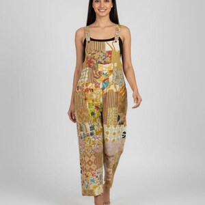May include: A patchwork jumpsuit in shades of yellow, beige, and brown. The jumpsuit features a variety of patterned fabric squares sewn together. It has wide legs and adjustable straps. The model is wearing a black top underneath.